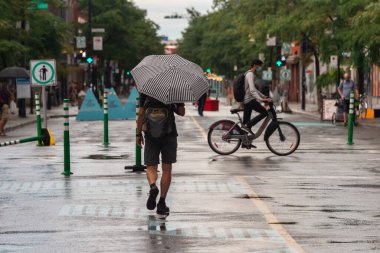 Montreal, CA - 30 Temmuz 2020: Mont-Royal Bulvarındaki adam yağmur ve fırtına sırasında şemsiye tutuyor