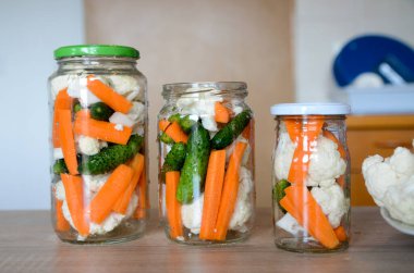Masadaki cam kavanozlarda sebze konserveleri.