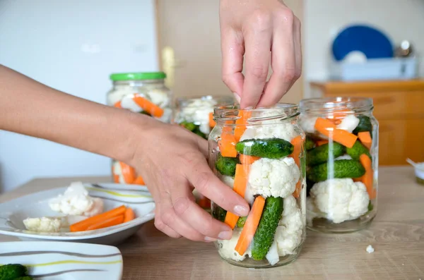 Home canning of vegetables in glass jars, human hands