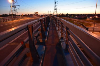 Güzel bir günbatımının arka planında üst geçit köprüsünde yürü