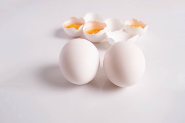 Çiğ beyaz kırık yumurta yumurta kabuğu yarısı ve hafif bir arka plan üzerinde iki bütün yumurta