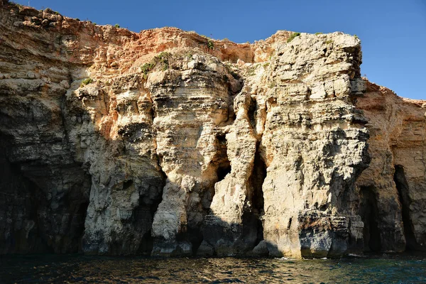 Cílfs altos con cuevas en la isla de Cominotto — Foto de Stock