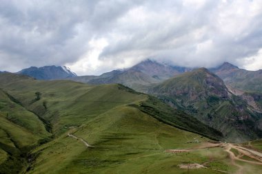Ana Kafkas (havza) sırtı. Georgia, Kazbegi Köyü (Stepantsminda). Mount Kazbek. Dağlar yaz Gürcü askeri yol. Güzel gökyüzü. Yeşil, yüksek dağlar. Tatil, zam. Gergeti