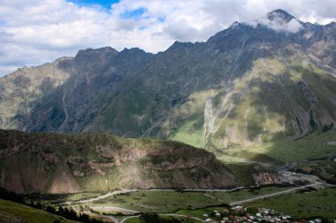 Ana Kafkas (havza) sırtı. Georgia, Kazbegi Köyü (Stepantsminda). Mount Kazbek. Dağlar yaz Gürcü askeri yol. Güzel gökyüzü. Yeşil, yüksek dağlar. Tatil, zam. Gergeti