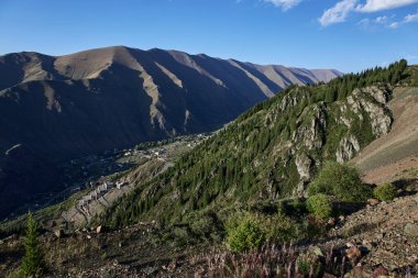 Dağ geçidinde bir köy ve dağ yamacında bir fabrika. Kırgızistan 'ın Ak-Tyuz köyü