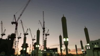 Medine, Suudi Arabistan-Aralık 2016: Silhouette İnşaat vinçleri, Müslüman hacıların ve açılmamış dev gölgelik şemsiye sırasında gündoğumu içinde Al Madinah, Suudi Arabistan.