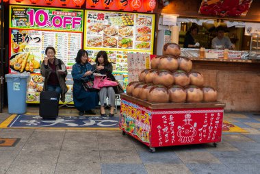 Osaka Naniwa-Ku, Osaka-Shi, Chome, Japonya-12 Kasım 2018 : Tanımlanamayan turist Osaka Kushikatsu Takoyaki Ajino Daimaru dükkanında takoyaki geleneksel Japon yemekleri yemek, Japonya.