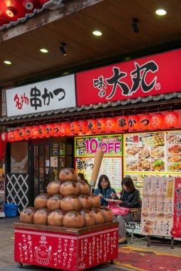 Osaka Naniwa-Ku, Osaka-Shi, Chome, Japonya-12 Kasım 2018 : Tanımlanamayan turist Osaka Kushikatsu Takoyaki Ajino Daimaru dükkanında takoyaki geleneksel Japon yemekleri yemek, Japonya.