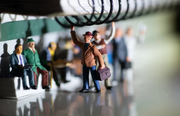 Juguete miniatura de personas que viajan desde el trabajo en un concepto de transporte público con iluminación lateral amarillenta por la noche: viaje en tren o autobús . — Foto de Stock