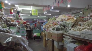 Kuala Terengganu, Malezya-Nisan 2019 : Kimliği belirsiz adam, malezyanın Kuala Terengganu'daki Payang Pazarı'nda ağırlıklı olarak balık bazlı kurutulmuş ve paketlenmiş yerel gıda satan tezgahlar arasında bir tramvay itiyor.