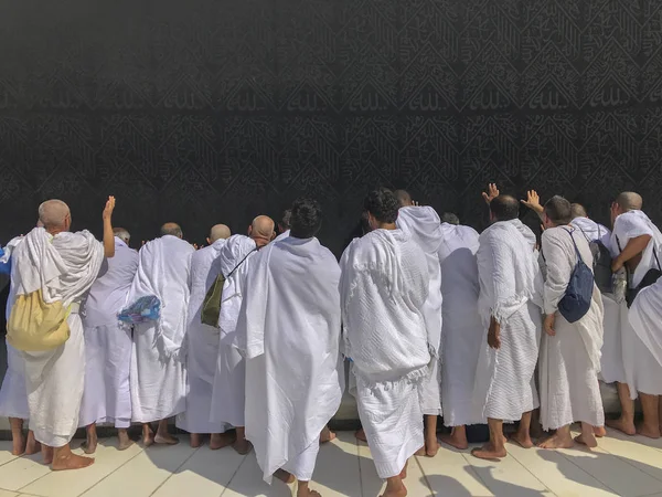 Unidentified Muslim pilgrims in white ihram touch black cloth of — Stock Photo, Image