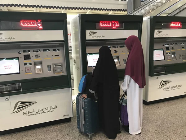 Duas senhoras muçulmanas não identificadas olham para uma nova máquina de distribuição de bilhetes automatizada na estação Madinah em Medina, Arábia Saudita . — Fotografia de Stock