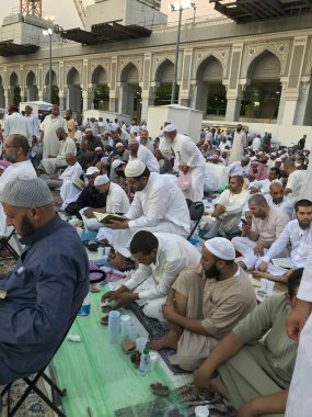 Mekke, Suudi Arabistan-Circa Haziran 2019: Kimliği belirsiz Müslüman erkekler Ramazan ayında Mescid-i Haram içinde oruç beklerken Kur'an-ı Kerim okuyup namaz kılıyor.