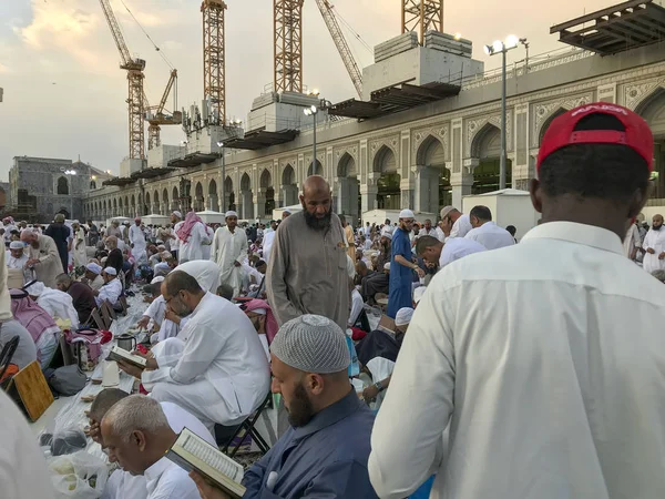 Mekke, Suudi Arabistan-Circa Haziran 2019: Kimliği belirsiz Müslüman erkekler Ramazan ayında Mescid-i Haram içinde oruç beklerken Kur'an-ı Kerim okuyup namaz kılıyor.