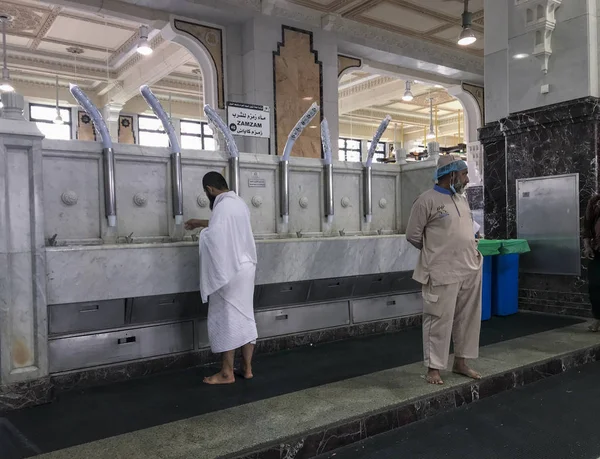 沙特阿拉伯麦加 2019年6月4日 工作人员看着 而一个穿着伊拉姆白衣的穆斯林朝圣者在沙特阿拉伯麦加的圣地清真寺内喝扎姆扎姆水 — 图库照片
