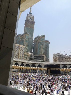 Mekke, Suudi Arabistan- 26 Ağustos 2019 : Hac hacıları, Suudi Arabistan'ın Mekke kentinde hac mevsiminde renkli şemsiyelerle su gibi sıcaktan kendilerini gölgelemişti. Arka planda Abraj al Bait kulesi.