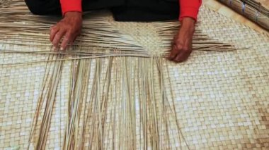 Terengganu, Malezya'da paspas dokuma uzman bir eski kadın elleri yakın çekim. Doğal bitki yapraklarından yapılan paspas çeşitli renk ve boyutlarda gelir.