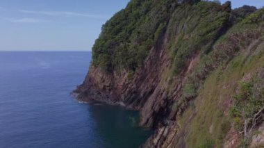Tehlikeli bir uçurumun yüksek açılı görüntüsünü ön planda kaya oluşumları ve kayalara çarpan dalgaların görüntüsünü yükselt.