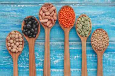 Vejetaryen kaynakları ahşap mavi arka plan üzerinde sağlıklı protein. Yeşil bezelye, nohut, kahverengi ve kırmızı mercimek, fasulye siyah ve kahverengi. Kapatın. Üstten görünüm veya düz.