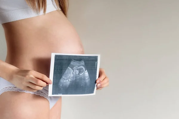 베이지색 배경에 초음파 스캐너의 사진으로 외관의 임신한 클로즈업 — 스톡 사진