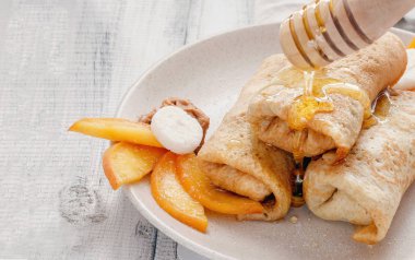 Ev yapımı krep veya şeftali, bal ve rustik ahşap arka plan üzerinde plaka üzerinde fıstık ezmesi ile Rus blini. Doldurulmuş Krep yerken üzerine seramik