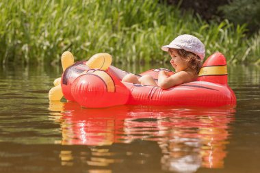 Sıcak yaz günü şişme kırmızı yerin suda oynarken mutlu küçük kız. Yüzmeyi öğrenmek. Çocuk su oyuncakları