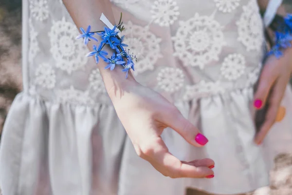 Blue snowdrops glued to girlish young hands with a bright manicure, day, close-up. Concept - love of nature, creative art
