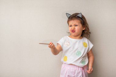 Kız somurtarak dudaklar ve ilginç duygu ile 3 yaşında tarafına gösterir ve yakın çekim bir işaretçi tutar şirin çocuk, portre, gün