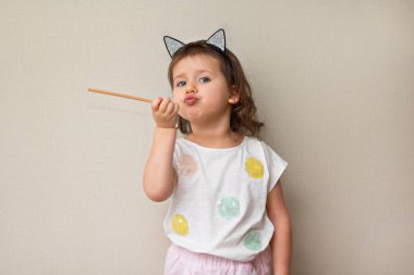 Kız somurtarak dudaklar ve ilginç duygu ile 3 yaşında tarafına gösterir ve yakın çekim bir işaretçi tutar şirin çocuk, portre, gün