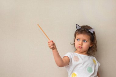 Kız somurtarak dudaklar ve ilginç duygu ile 3 yaşında tarafına gösterir ve yakın çekim bir işaretçi tutar şirin çocuk, portre, gün