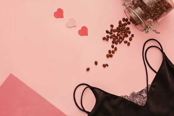 Women's dress for sleep, diary and scattered coffee on a powdery pink background, flatlay, copyspase, closeup