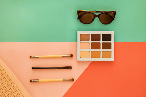 Palette of shadows for a make-up and female trend accessories, on a geometrical multi-colored background, minimal, art, flatlay