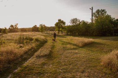 çayırda gün batımında bir adam ve safkan bir köpek yavrusu silueti