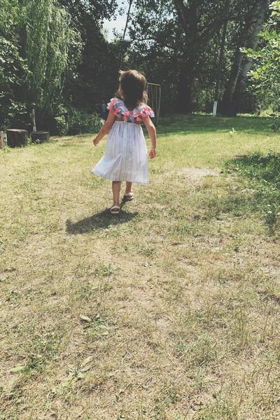 Menina correndo na grama verde. Linda noite quente de verão . — Fotografia de Stock