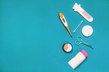 Yeni doğmuş bir bebeğin bakımı için aksesuar, makas, tarak, krem, toz, termometre, çubuk, pamuk, mavi bir turkuaz arka plan, yassı