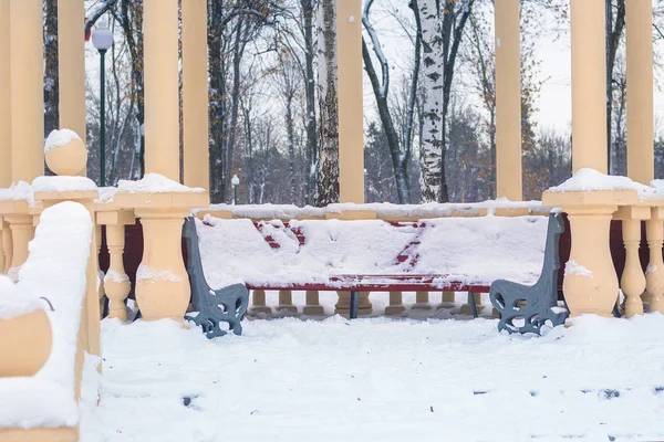 Un banco en el parque cubierto de nieve, temporada de invierno, remoción de nieve — Foto de Stock
