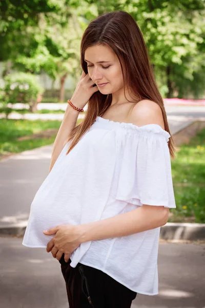 Joven mujer embarazada hermosa con el pelo largo y oscuro al sol — Foto de Stock