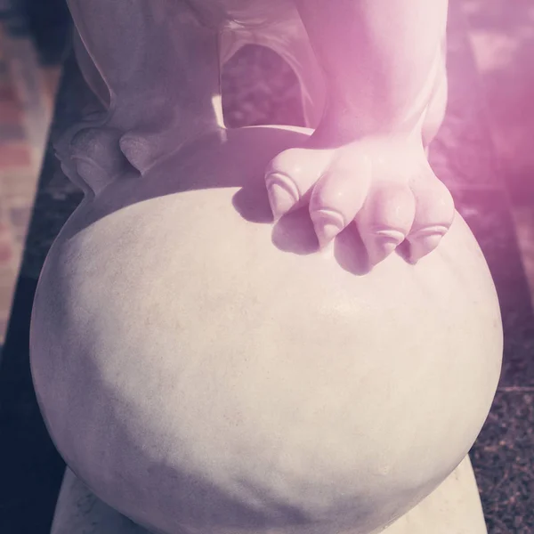 Escultura de león blanco, patas y garras en la pelota. Tonificado. Cállese. — Foto de Stock