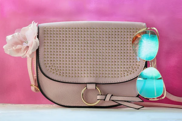 Ladies Fashion Accessories. Pink Clutch, sunglasses on white and pink background. Pastel colors Trend