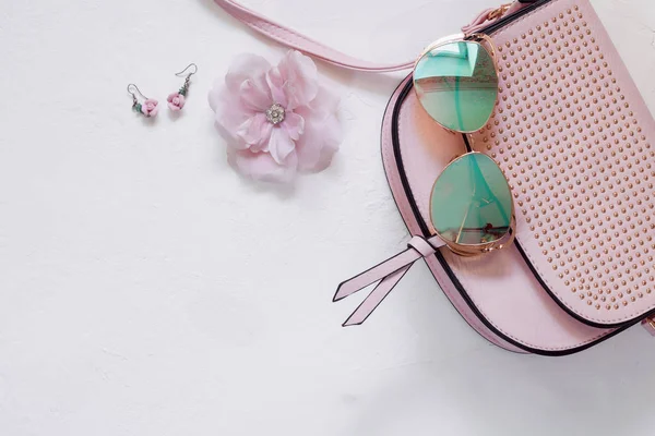 Ladies Fashion Accessories. Pink Clutch, sunglasses, earrings, hairpin rose on a white background. Pastel colors Trend. Flatlay