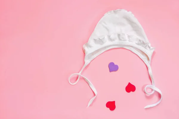 Gorra de bebé blanca de verano sobre un fondo rosa con corazones, estilo minimalista, flatlay, copyspase — Foto de Stock