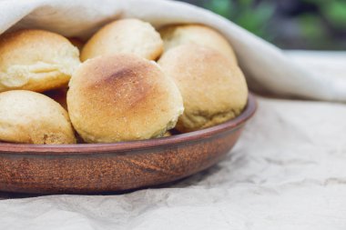 Ev yapımı ekmek ya da topuz ahşap arka plan üzerinde bir kil plaka. Homemade pişirme