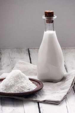 Şişe ev yapımı hindistan cevizi sütü ve şalgam arka planında bir tabakta talaş.