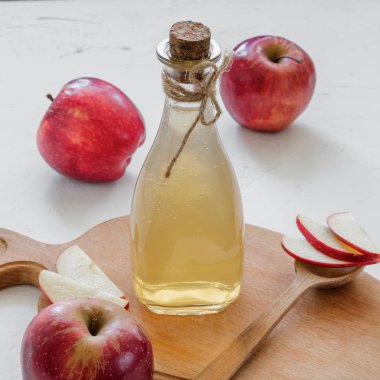 Elma sirkesi. Beyaz arka planda bir şişe elmalı organik sirke ve çiğ kırmızı elma. Sağlıklı organik gıda.