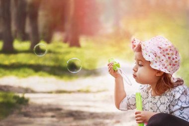 Küçük kız baloncukları doğaya doğru üflüyor. Yakın plan..