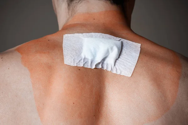 Pronto soccorso dopo una ferita profonda, un cerotto sulla schiena di un uomo — Foto Stock