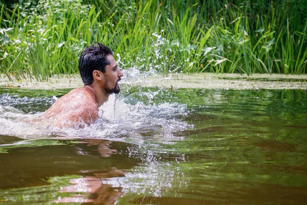 The young man Caucasian appearance with a beard swimming in the river