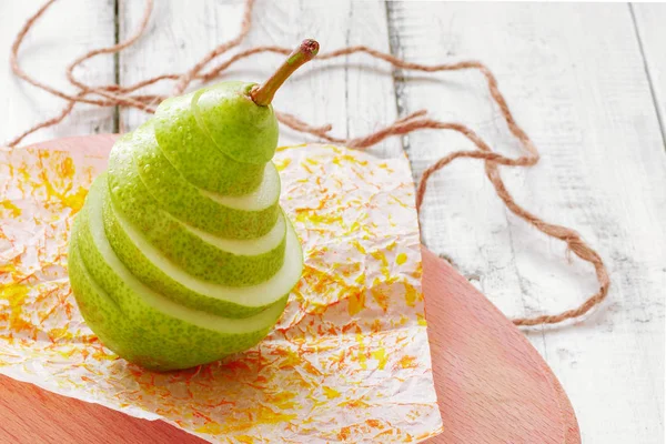Green fresh pear cut into pieces, which are stacked on top of each other. Pear slices. Wooden background. In rustic style
