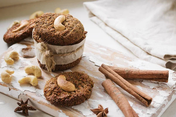 Homemade nutty vegan cinnamon cookies on white beige wooden board, close-up, natural light