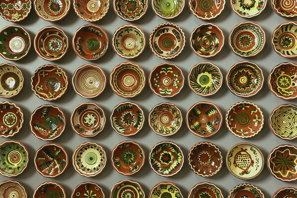 Opishnya, Ukraine - July 4, 2019: group of clay bowls with patterns hanging on a wall at the National Museum of Pottery